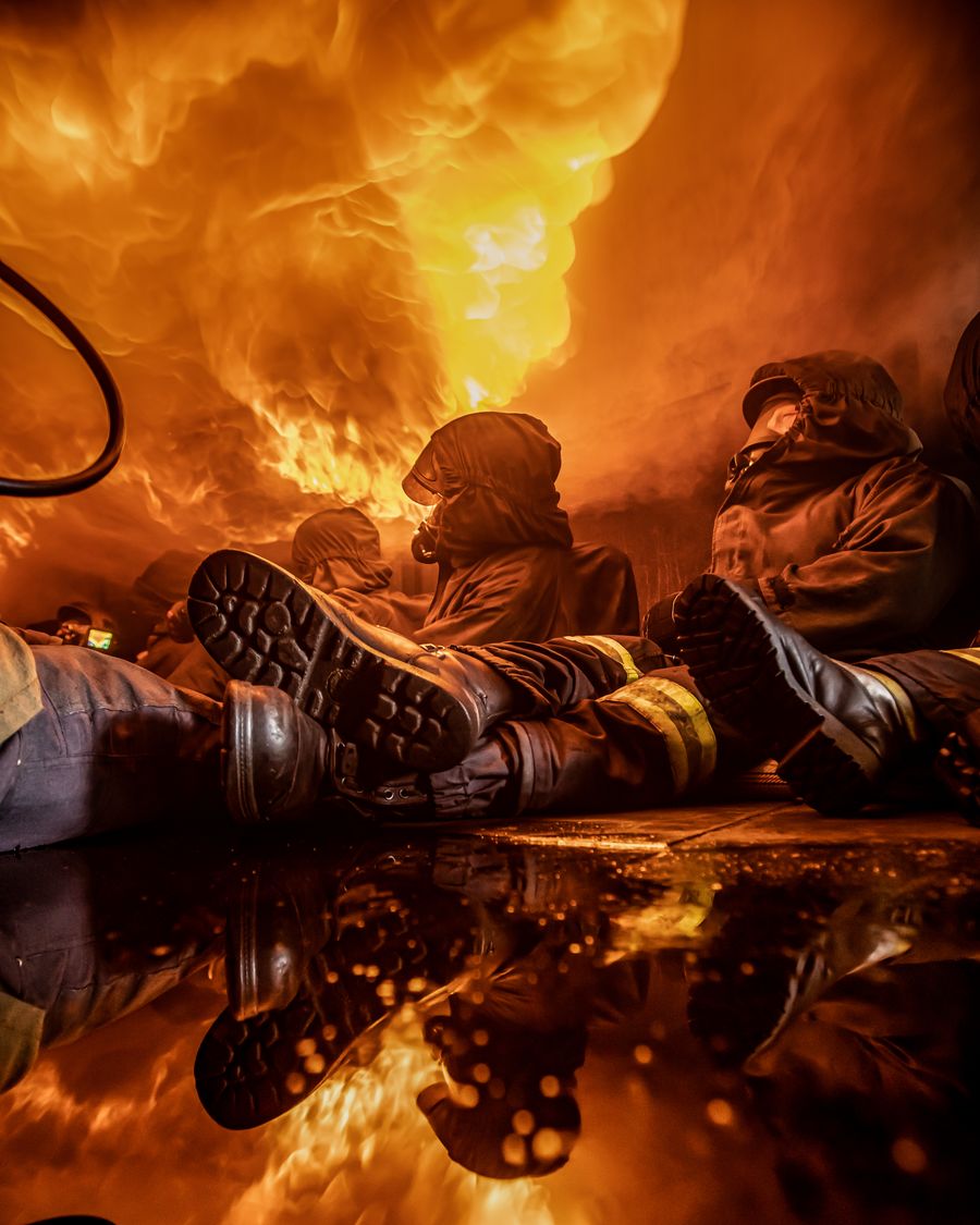 Einsatzkräfte in Feuerwehrschutzkleidung bei einer Heißausbildung mit Flammen und Brandrauch