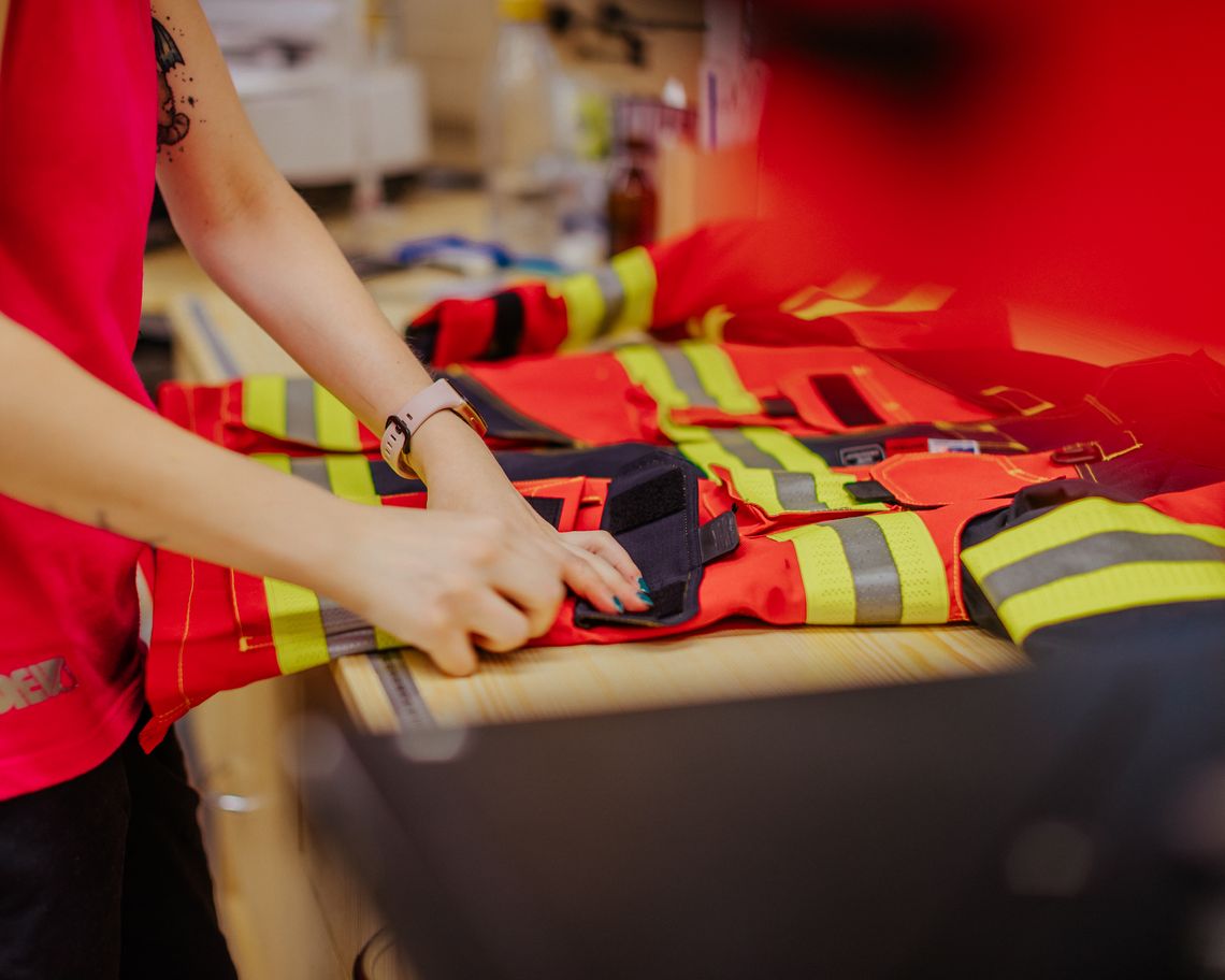 Sichtprüfung einer Feuerwehrjacke mit Reflexstreifen und Taschen auf dem Arbeitstisch